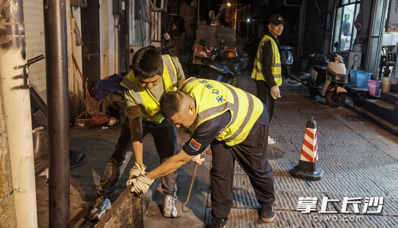 7日晚11时，天心区市政设施维护排渍科工作人员在小桥子巷检查雨水井淤积情况。均为长沙晚报全媒体记者 蒋志斌 摄