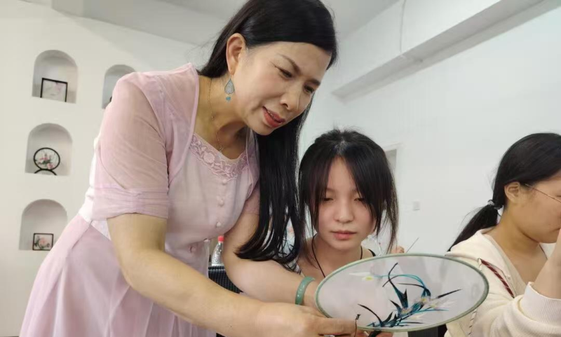 江再红指导学生动手尝试刺绣。