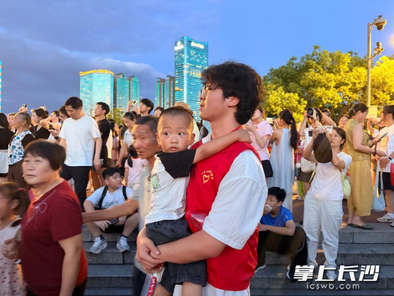长沙学院青年志愿者刘历豪正在安抚孩子情绪。