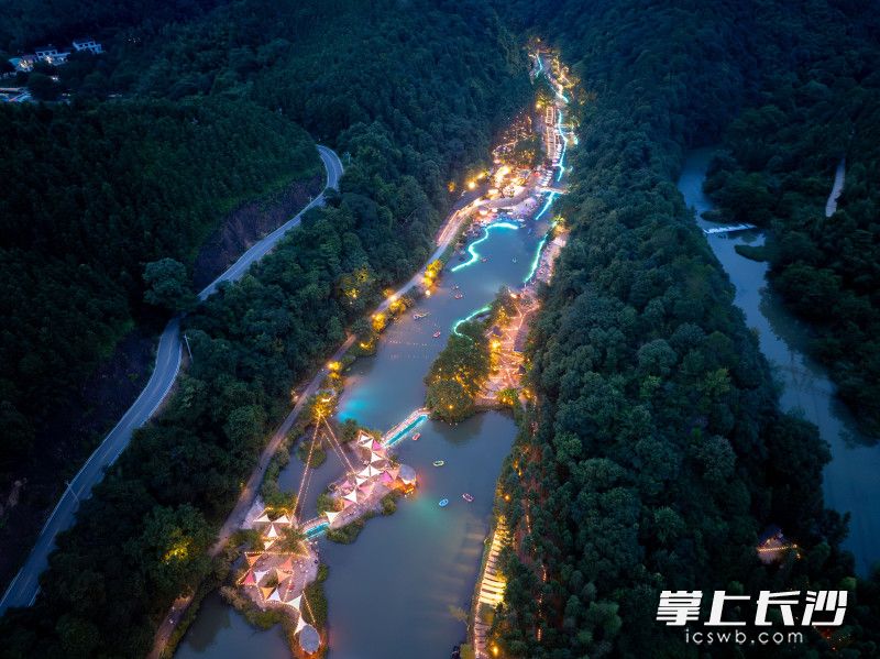 傍晚时分,山谷里灯火次第点亮。蓝绿色光影铺洒在河道之上,形成独具特色的夜光漂流景观。