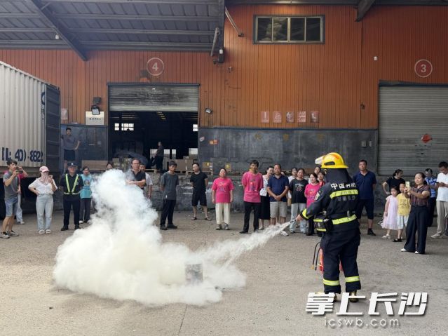 消防员现场演示灭火器使用方法。