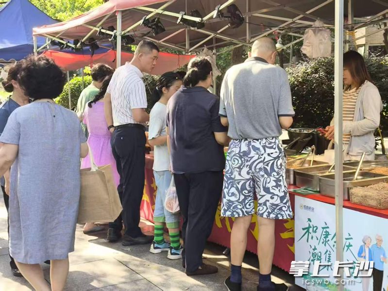 居民们在美食好物摊位前选购。通讯员供图 居民们在美食好物摊位前选购。通讯员供图