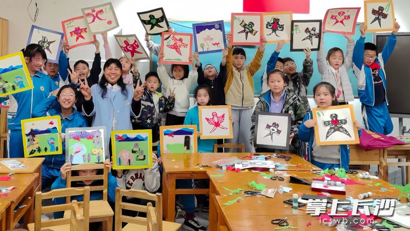在国防科技大学附属小学的剪纸课上，孩子们展示剪纸作品。