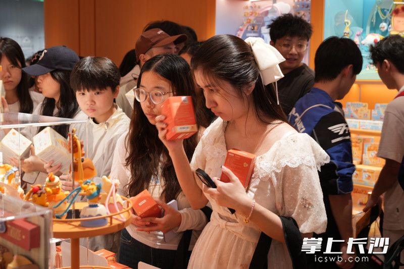 顾客正在摇晃盲盒来猜测盒内的款式。