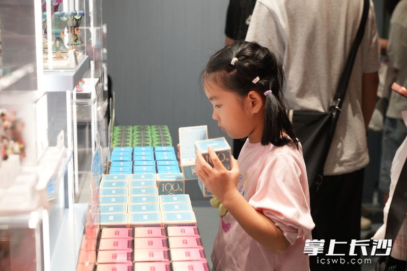 小女孩正在通过摇晃盲盒来推测自己想要的款式。