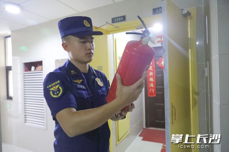 防火监督员在小区检查灭火器是否过期失效。 防火监督员在小区检查灭火器是否过期失效。