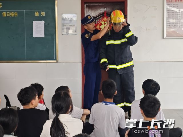 指导学生体验穿戴灭火救援服。 长沙晚报通讯员 徐文俊 供图 指导学生体验穿戴灭火救援服。 长沙晚报通讯员 徐文俊 供图