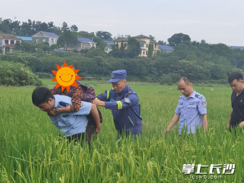 辅警桂福昌背起老人从田地走向安全区域。 望城公安供图 辅警桂福昌背起老人从田地走向安全区域。 望城公安供图