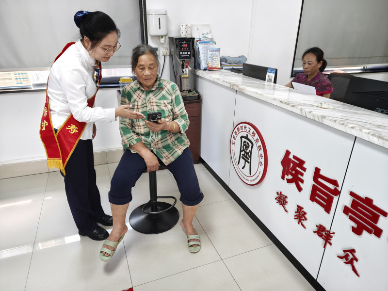 工作人员为高龄老人办理相关业务提供贴心协助，依托优质数智化服务为老年群众排忧解难。资料照片
