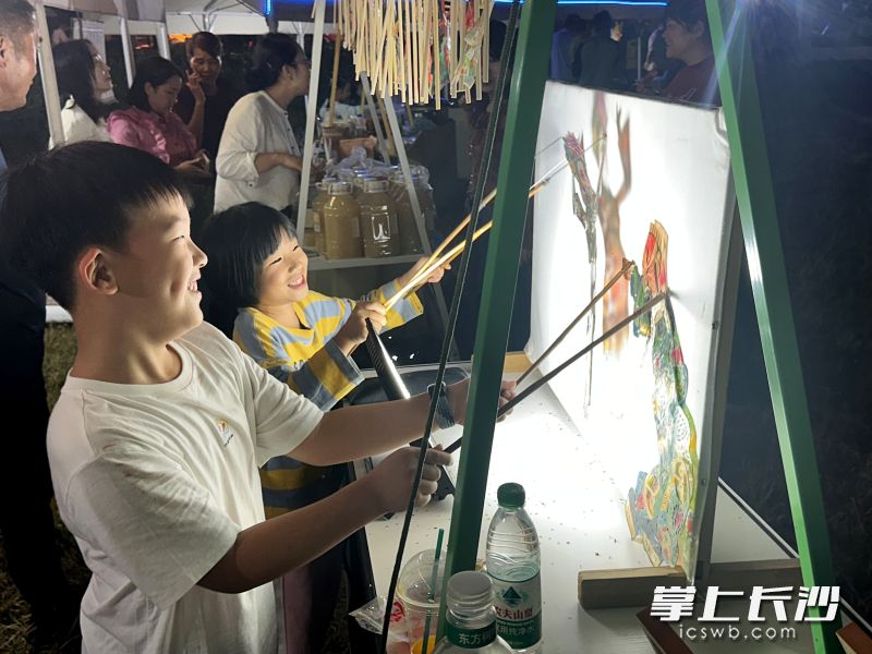 在摊位前,孩子们开心地操作皮影。湘江早报全媒体记者 黄荣佳 摄 在摊位前,孩子们开心地操作皮影。湘江早报全媒体记者 黄荣佳 摄