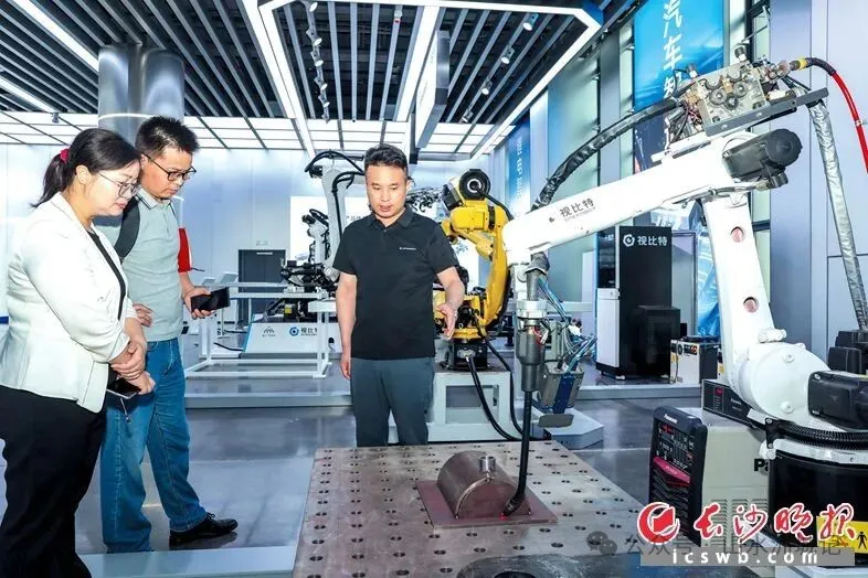 湖南视比特机器人有限公司董事长兼CEO邓文平（右一）向采访组介绍公司产品“智能焊接工作站”。董阳 摄