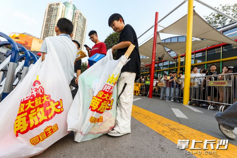 出场的小游客手里提着大袋零食。