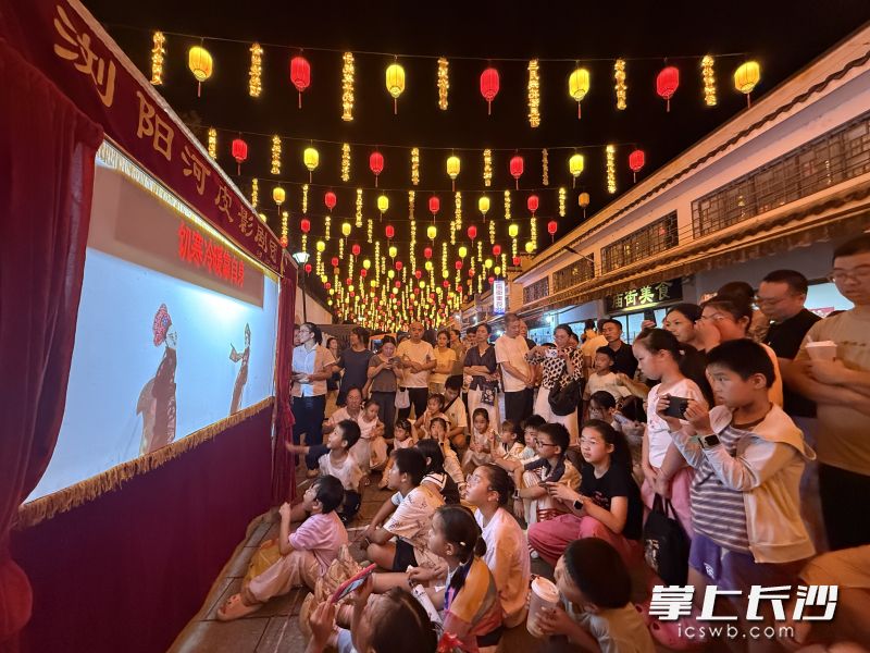 华灯初上，三仙街皮影戏表演吸引众多游客驻足观看。