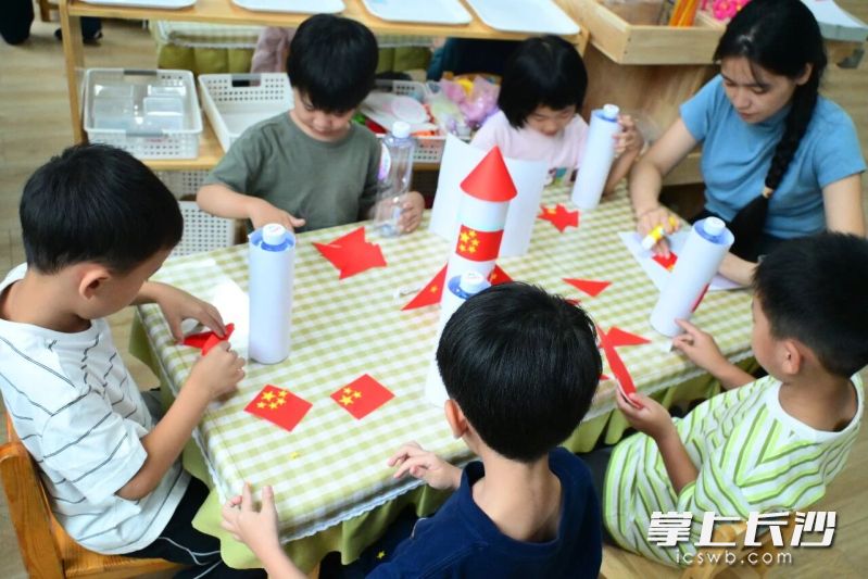 幼儿园小朋友在老师带领下，用废旧材料拼搭火箭模型。