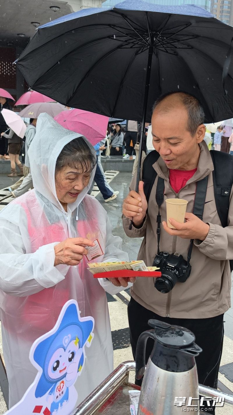 唐灼灼(左)冒雨为游客服务。 唐灼灼(左)冒雨为游客服务。