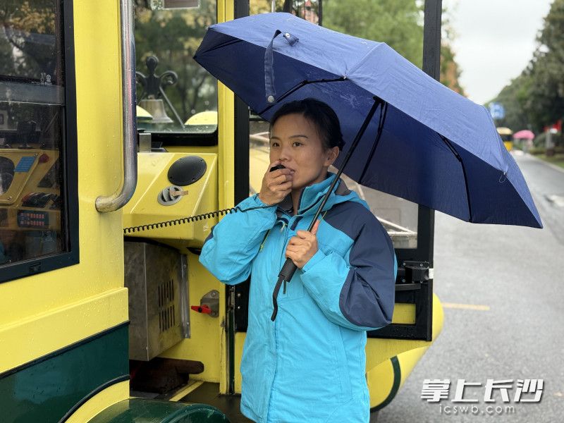 城发橘子洲观光小火车驾驶员周姣正在雨中引导游客安全乘车。
